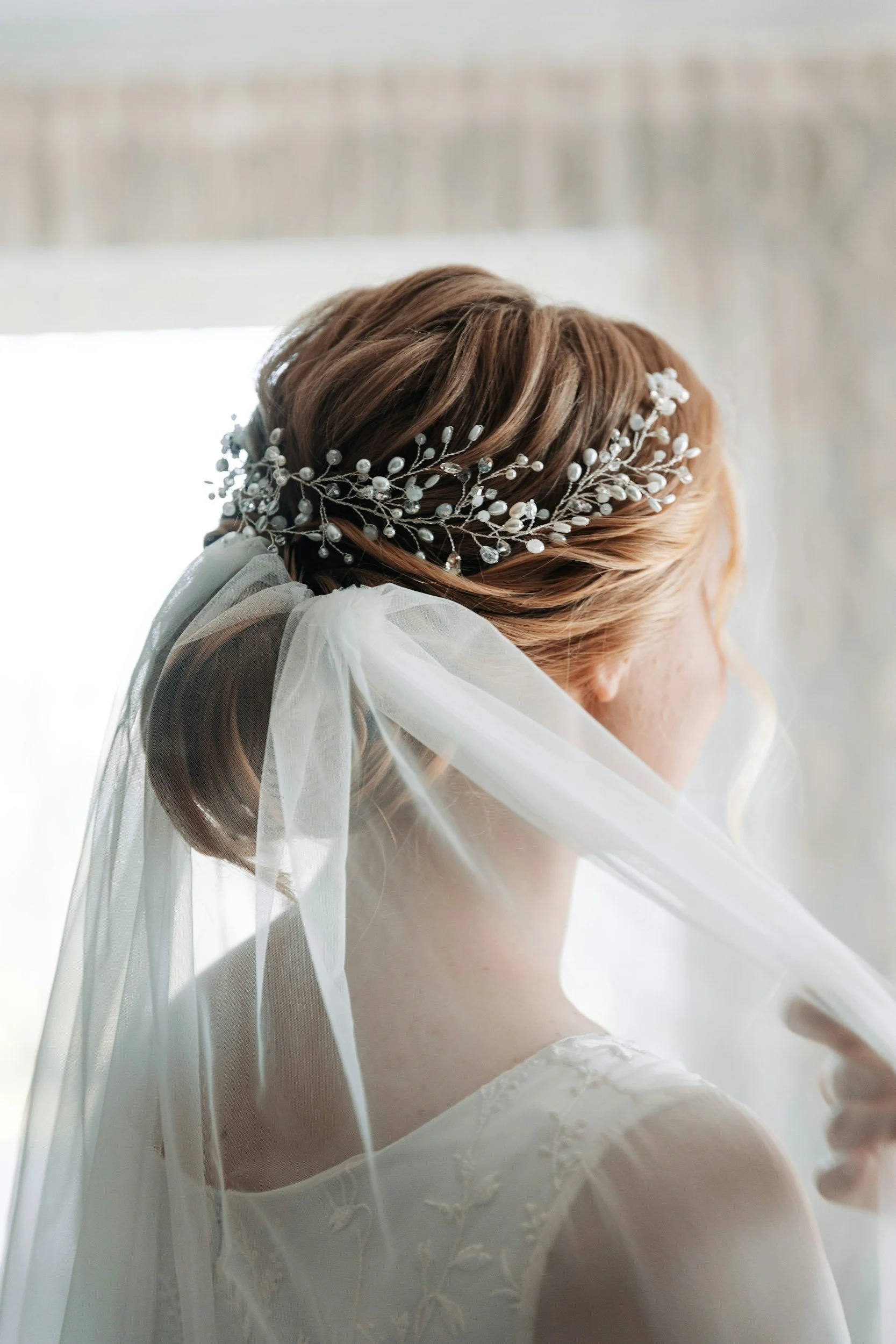 Elegant bridal hairstyle with pearl and crystal hair accessory, veil and lace wedding dress by Glamour Tribe.
