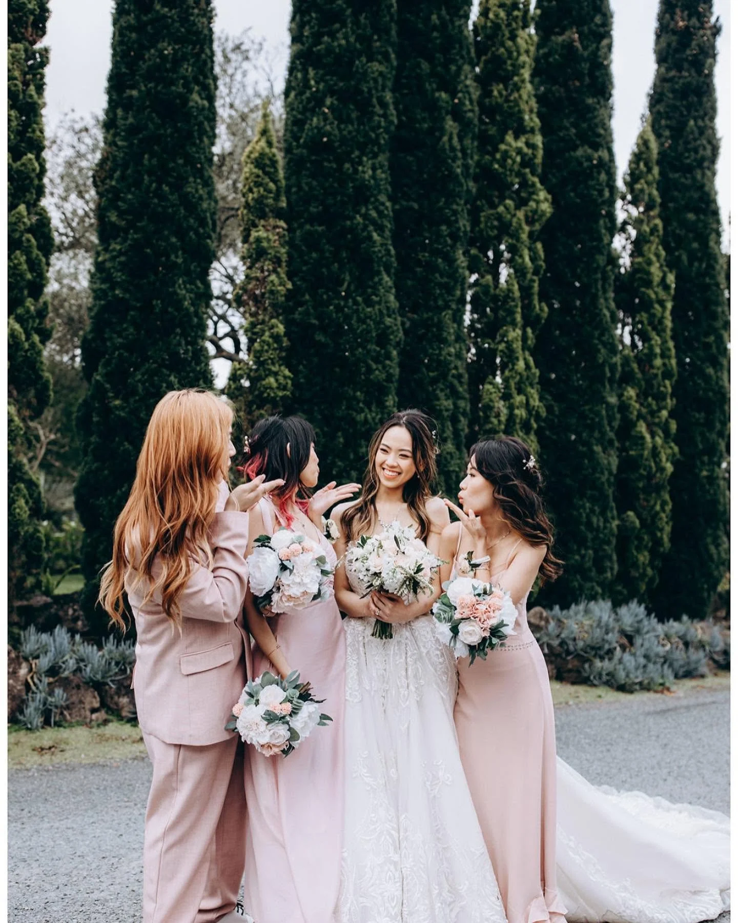 “Bride with bridesmaids holding bouquets at an outdoor wedding