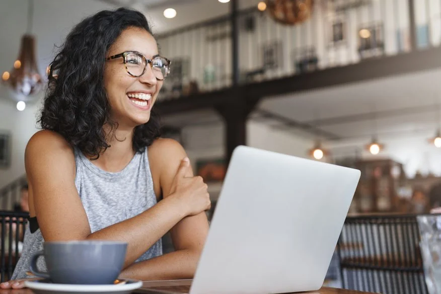 happy girl sitting in cafe on her laptop