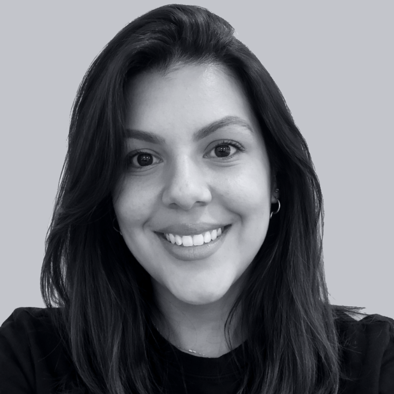 A young woman with long dark hair and a bright smile, wearing a black top, against a light background.