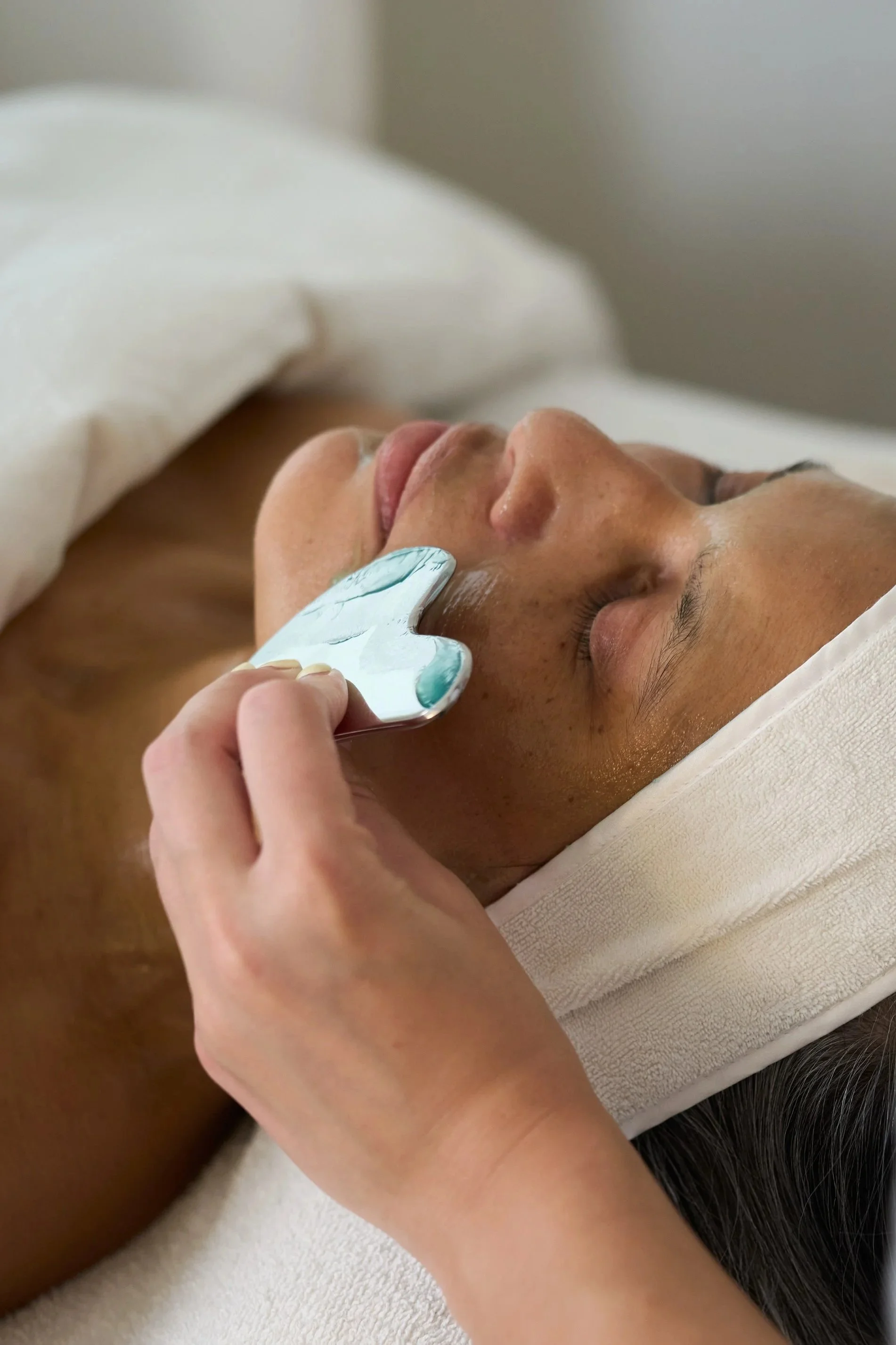 Person receiving a locals only facial treatment or skincare treatment at local skin bar while lying down with eyes closed.