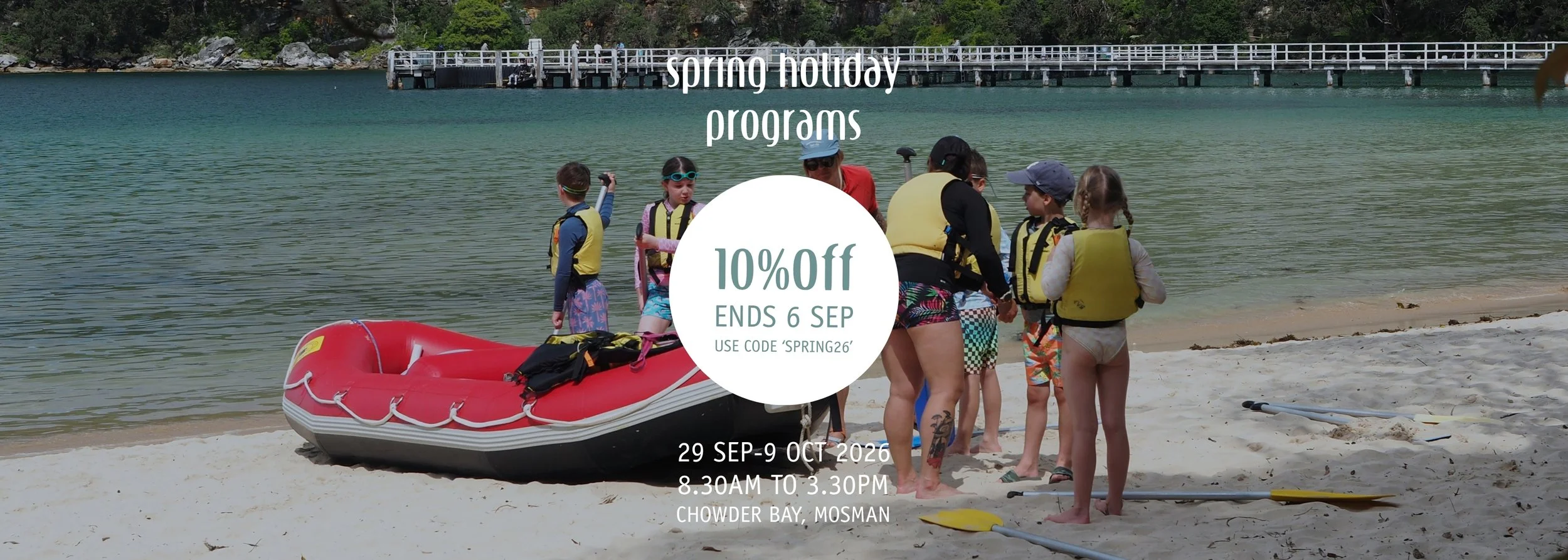 10% off spring school holiday programs at Saltwater School Chowder Bay from 28 September to 9 October. Use code Spring26, offer ends 6 September. Photo of instructors and kids n the beach getting ready to go rafting. 