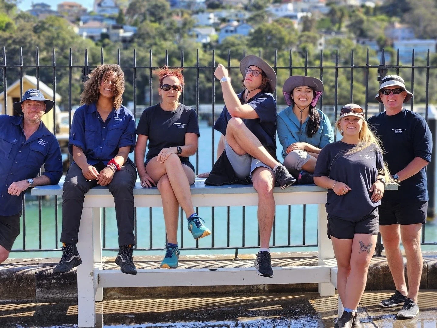 Land's Edge Foundation Saltwater School team sitting on a table in front of water and smiling at Chowder Bay