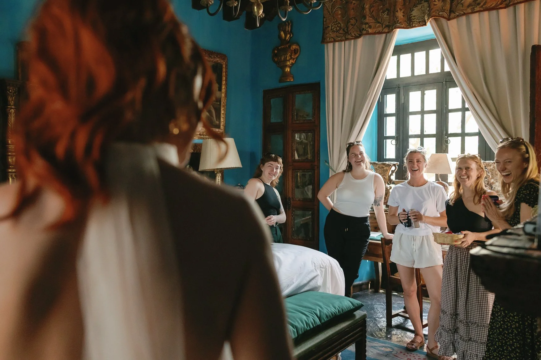 Group of women laughing together in an ornate blue-walled room in the bridal suite of casa hyder
