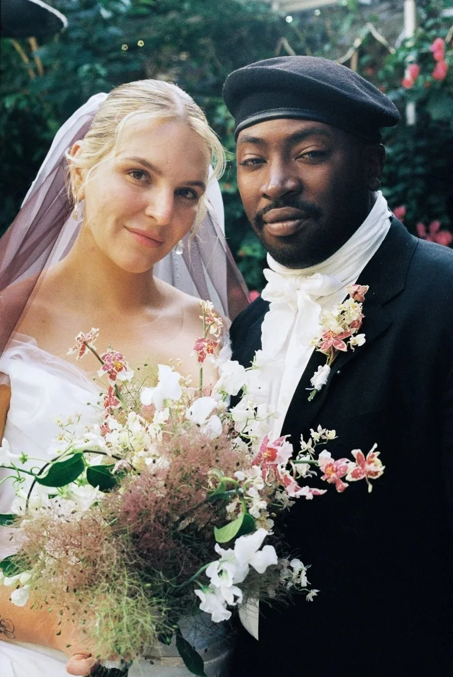 A fashion forward bride and groom posing closely in an editorial style on their wedding day in Topanga Canyon, captured on 120 film, against a garden background.