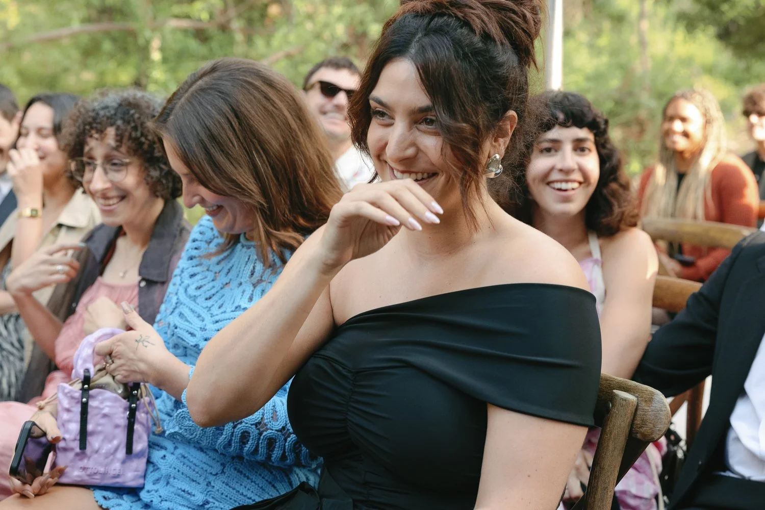 Group of women sitting outdoors, smiling and enjoying a social event.