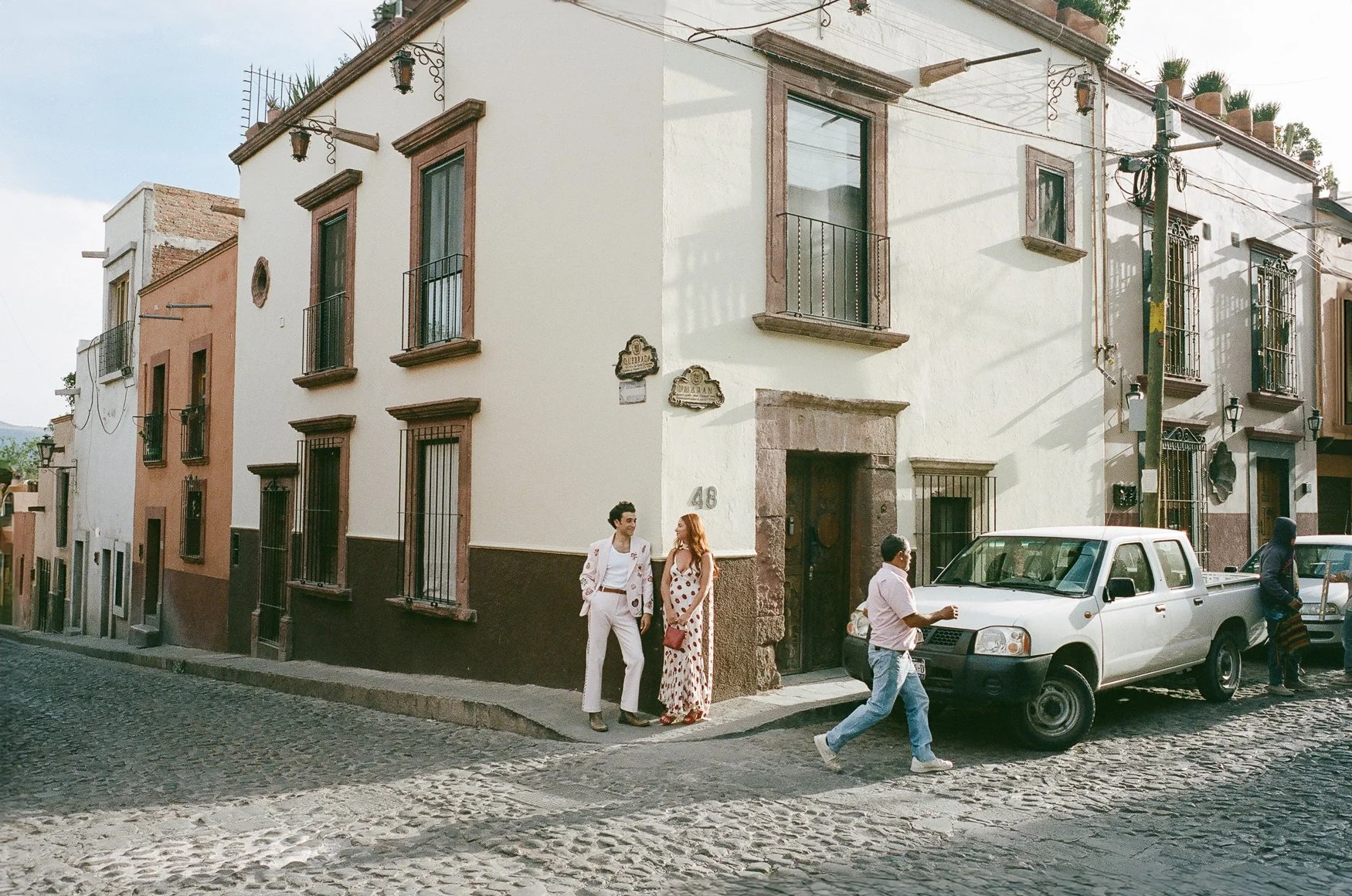 People walking beside colorful colonial buildings on a cobblestone street in Mexico