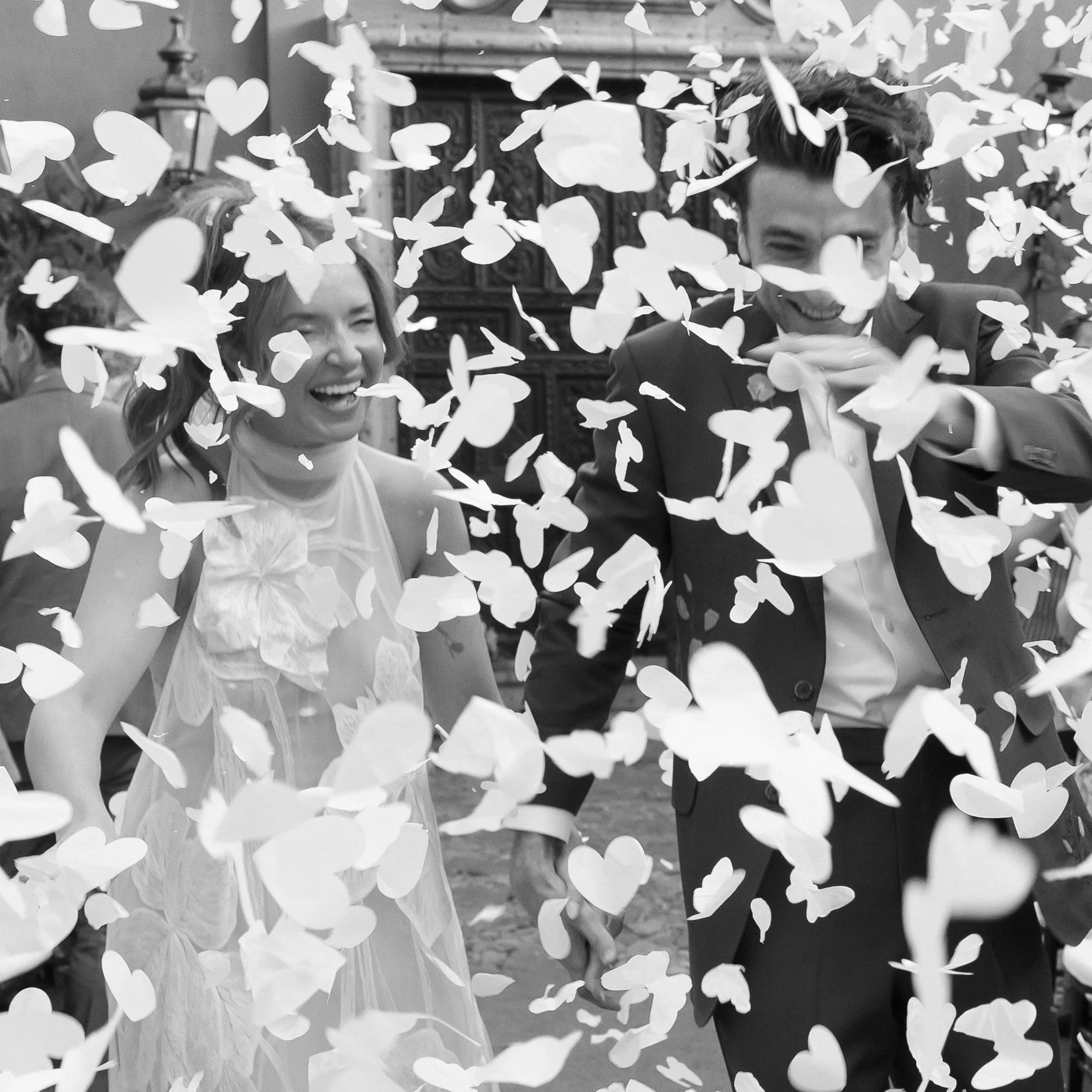 Newlywed couple laughing as flower petals fall around them during a wedding celebration at Casa Hyder