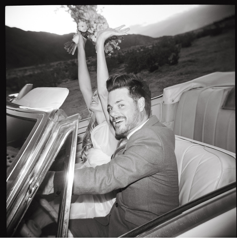 A joyful couple in vintage convertible car driving away from their Palm Springs Elopement
