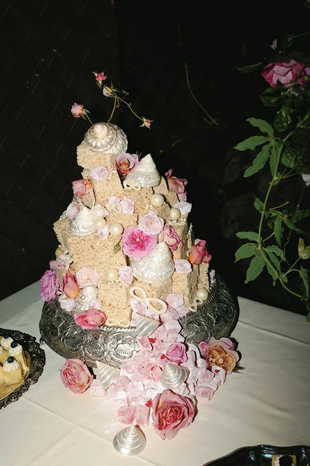 Decorative dessert display with pink roses, seashell decorations, and pinker candies placed on a silver tray