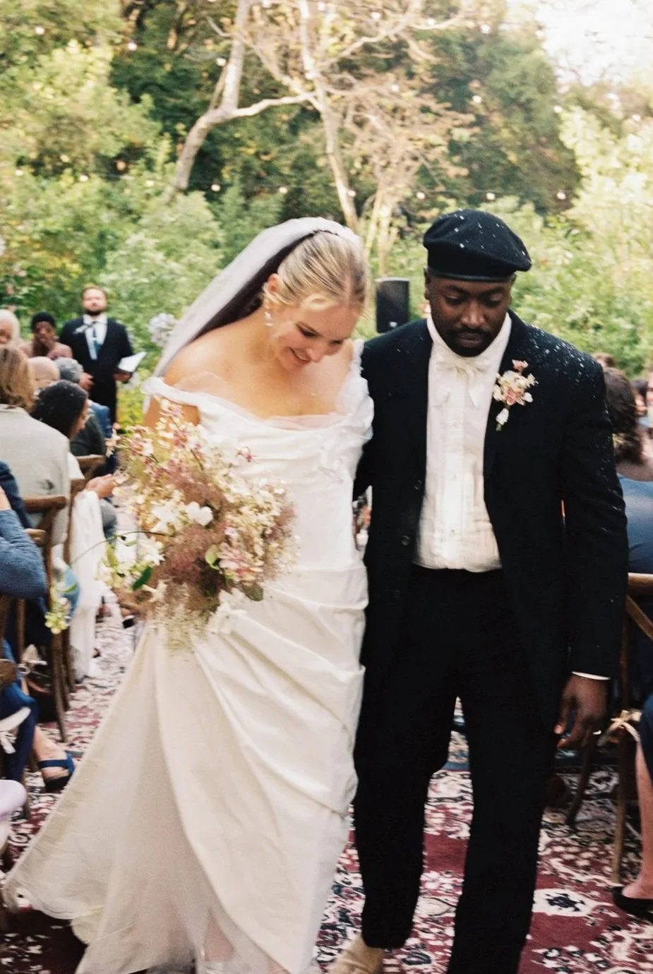 A bride and groom during their recessional with a petal toss captured on film.