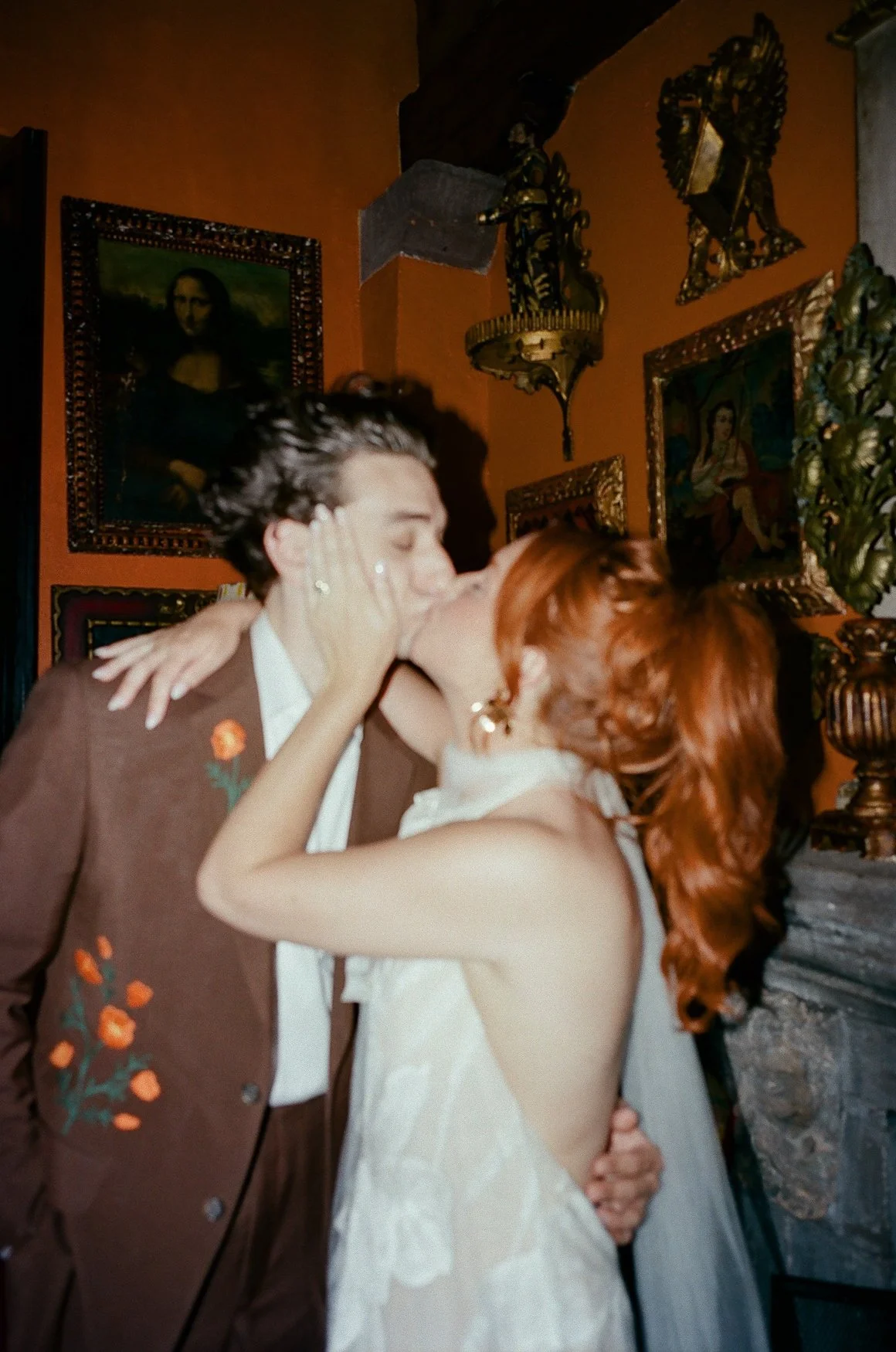 Couple kissing in an ornate maximalist room at Casa Hyder in san Miguel de allende decorated with framed paintings, sculptures, and antique furnishings
