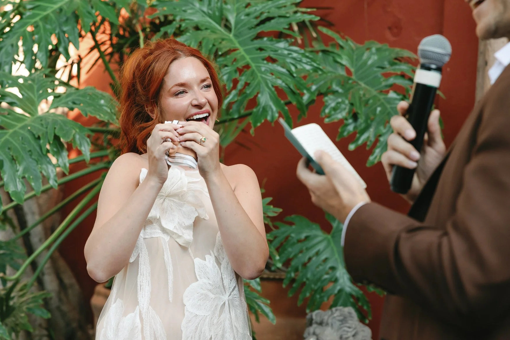Smiling red-haired bride during the reading of the grooms vows