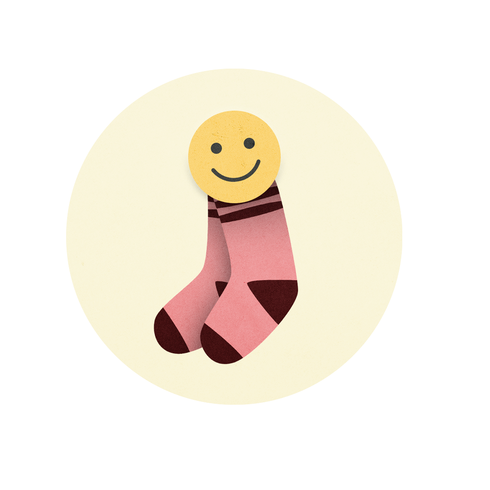 A pair of pink socks with brown accents and a smiley face sticker on top, set against a light-colored background.