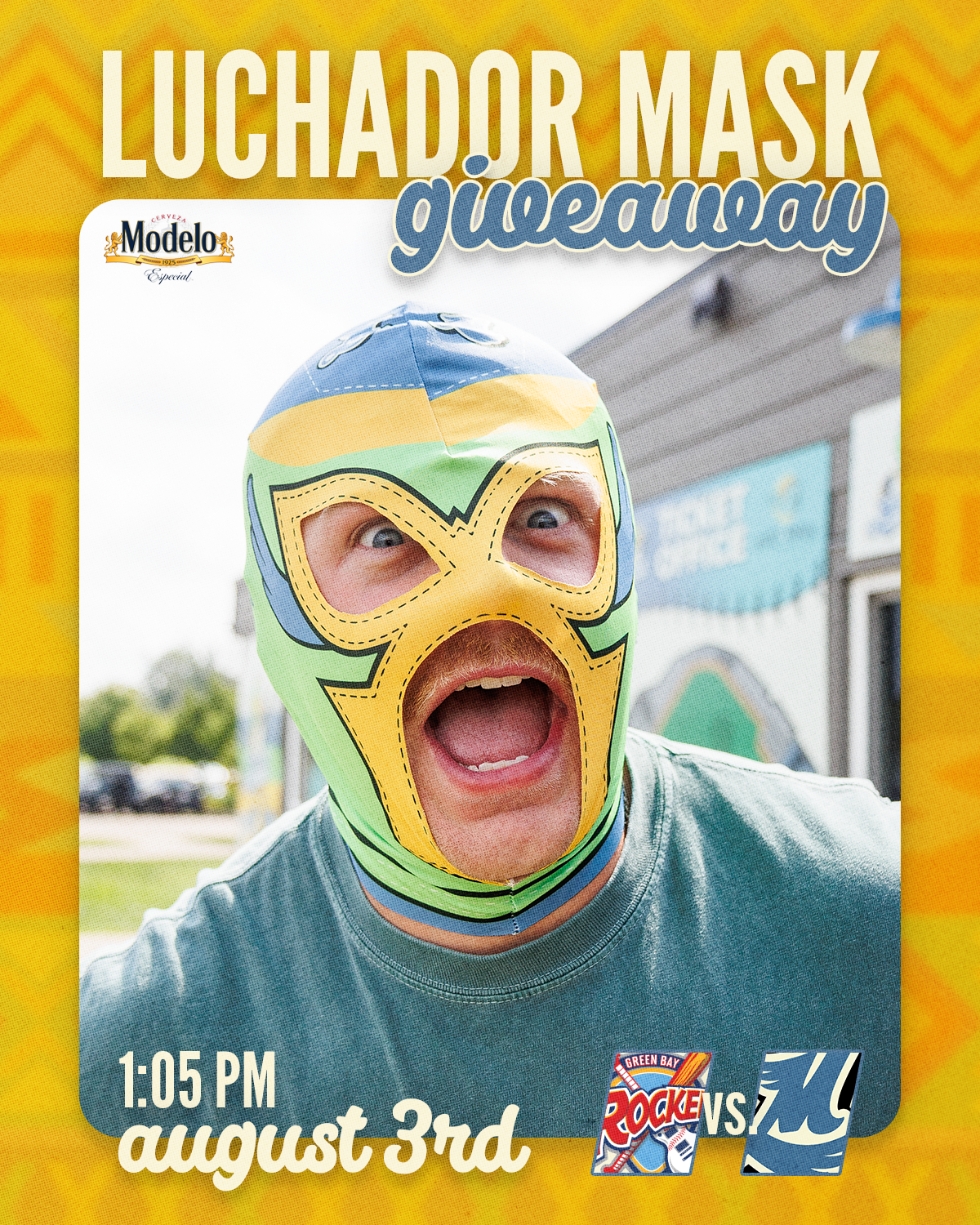 A person wearing a colorful luchador mask with open mouth and wide eyes, standing outdoors with a building and cars in the background.