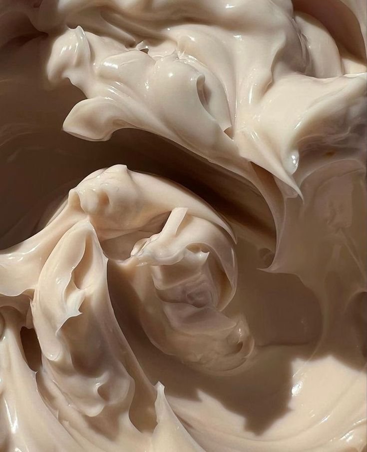 Close-up of smooth, creamy beige substance, possibly lotion or whipped cream.