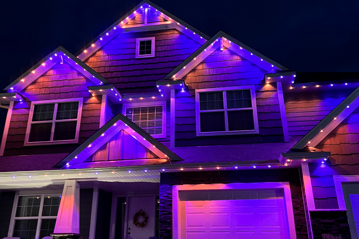 LED roofline install on a Eau Claire home with multicolor Halloween display in fresh snow