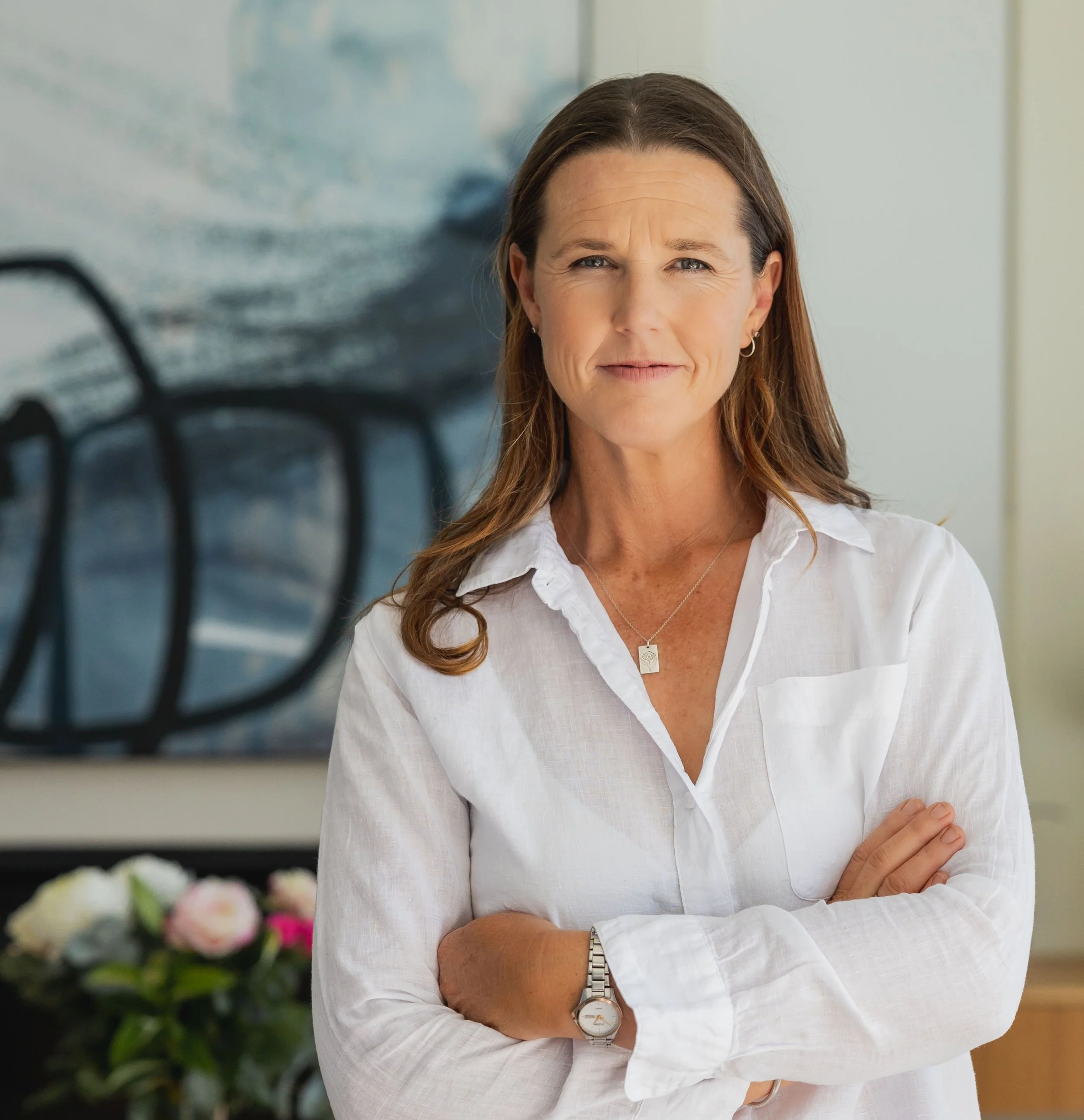 Authoritative portrait of Lucy Peel in a bright modern office with an abstract painting and pink flowers in the background.