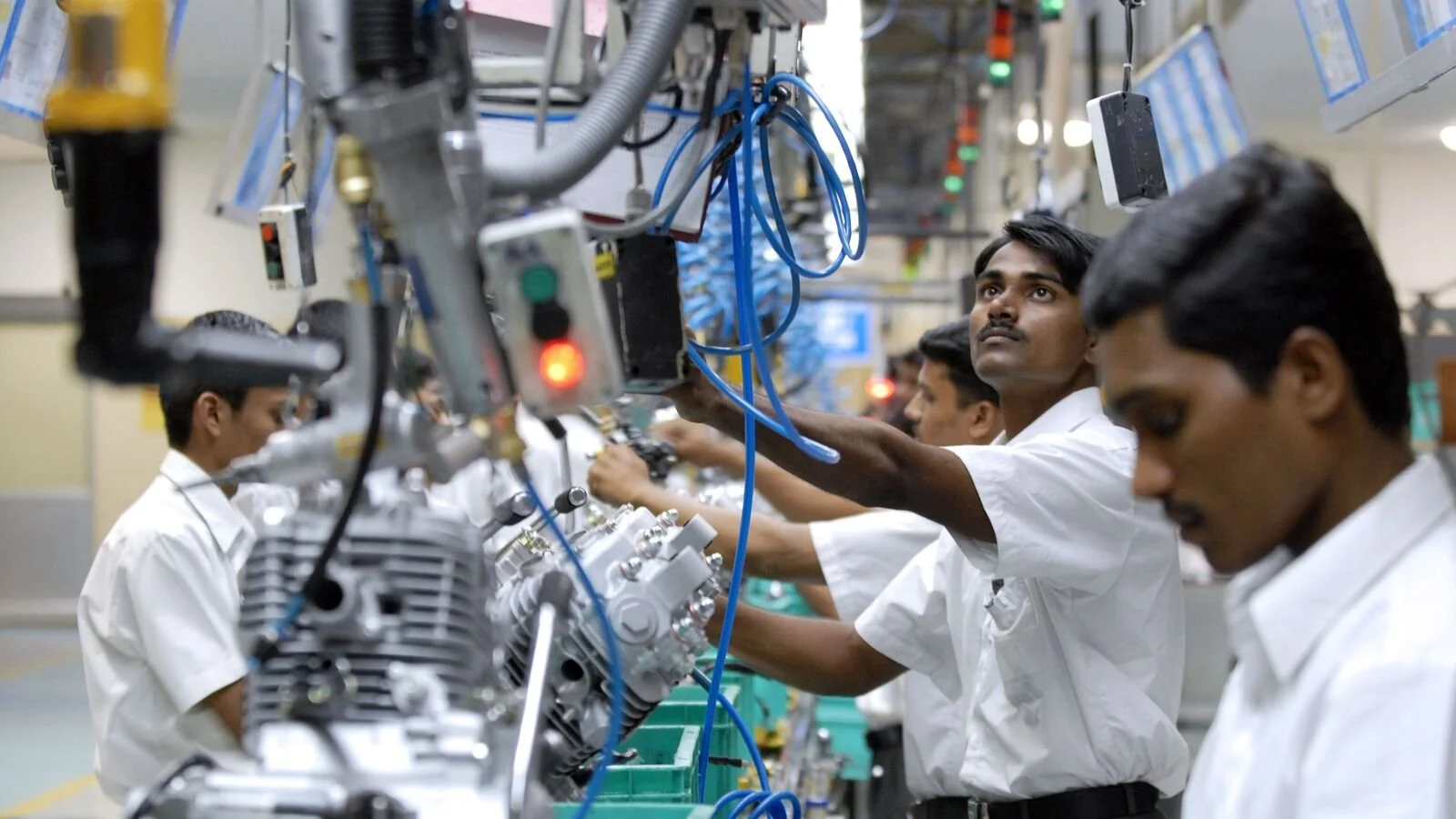 Factory workers assemble motorcycle engines on a production line at a Bajaj Auto manufacturing plant in India