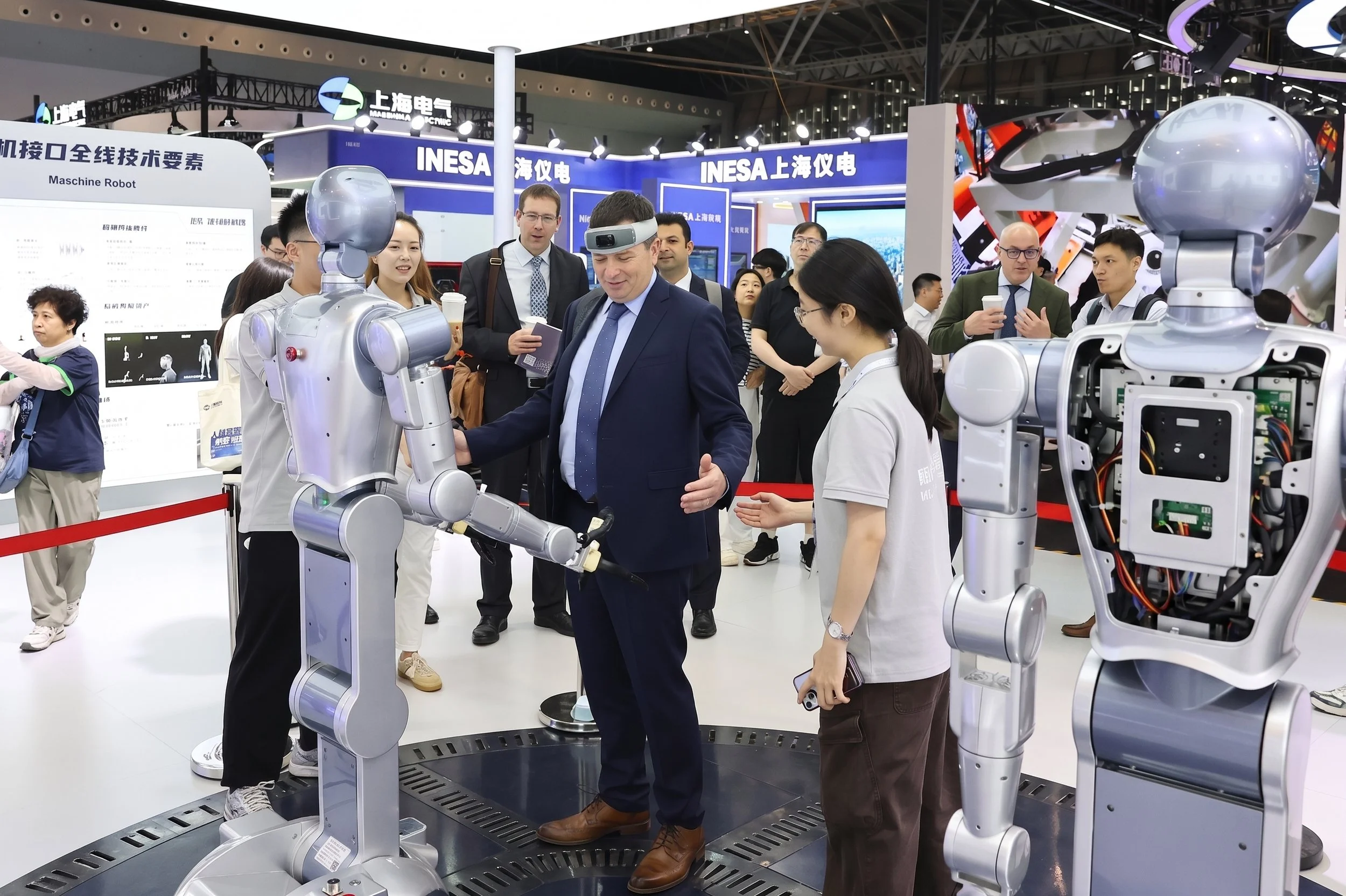 Un dirigeant occidental interagit avec un robot humanoïde INESA au salon international de la technologie de Shanghai, symbole de l'innovation chinoise en IA et robotique