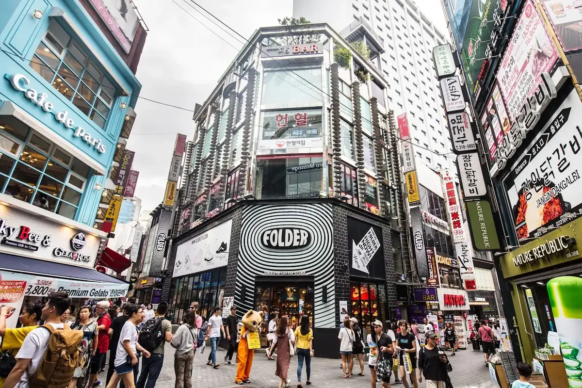 Clients dans une rue de Myeongdong à Séoul bordée de boutiques de beauté, de gastronomie et de mode coréennes (Hallyu)