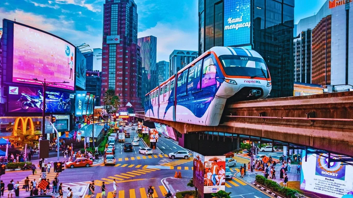 A vibrant cityscape with tall buildings, billboards, and a monorail train running above the busy streets filled with cars and pedestrians. Learning Expedition