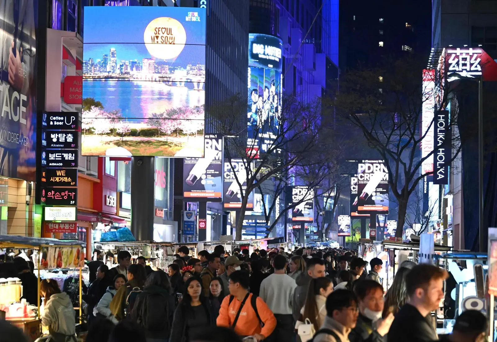 Foule sous des écrans publicitaires numériques à Myeongdong, quartier commerçant de Séoul