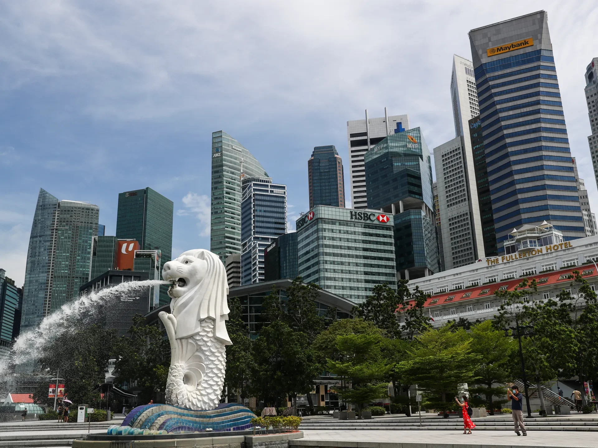 The Merlion statue with Singapore's financial district skyline in the background, including HSBC and Maybank towers
