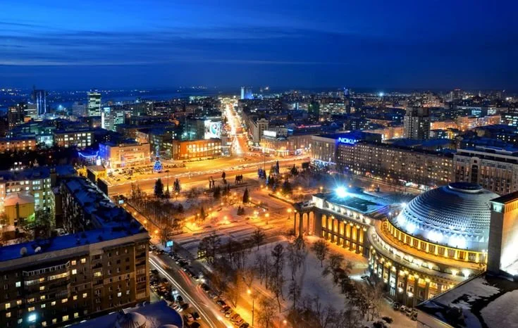 Night view of a cityscape with illuminated streets, buildings, and a prominent domed structure in the foreground, under a dark blue sky. Learning Expedition