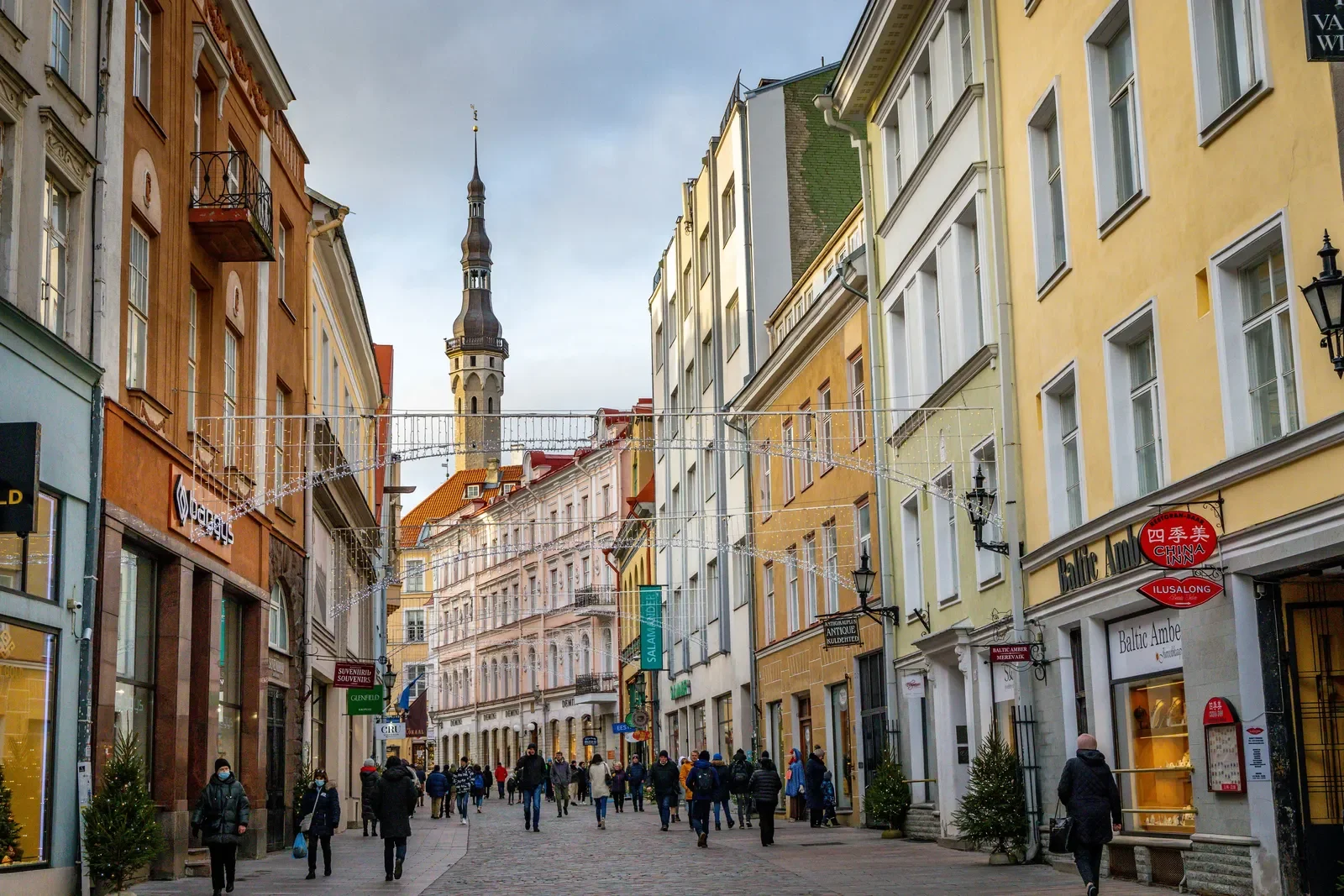 A bustling pedestrian street lined with colorful historic buildings, Christmas decorations, and a tall church steeple in the background. Learning Expedition