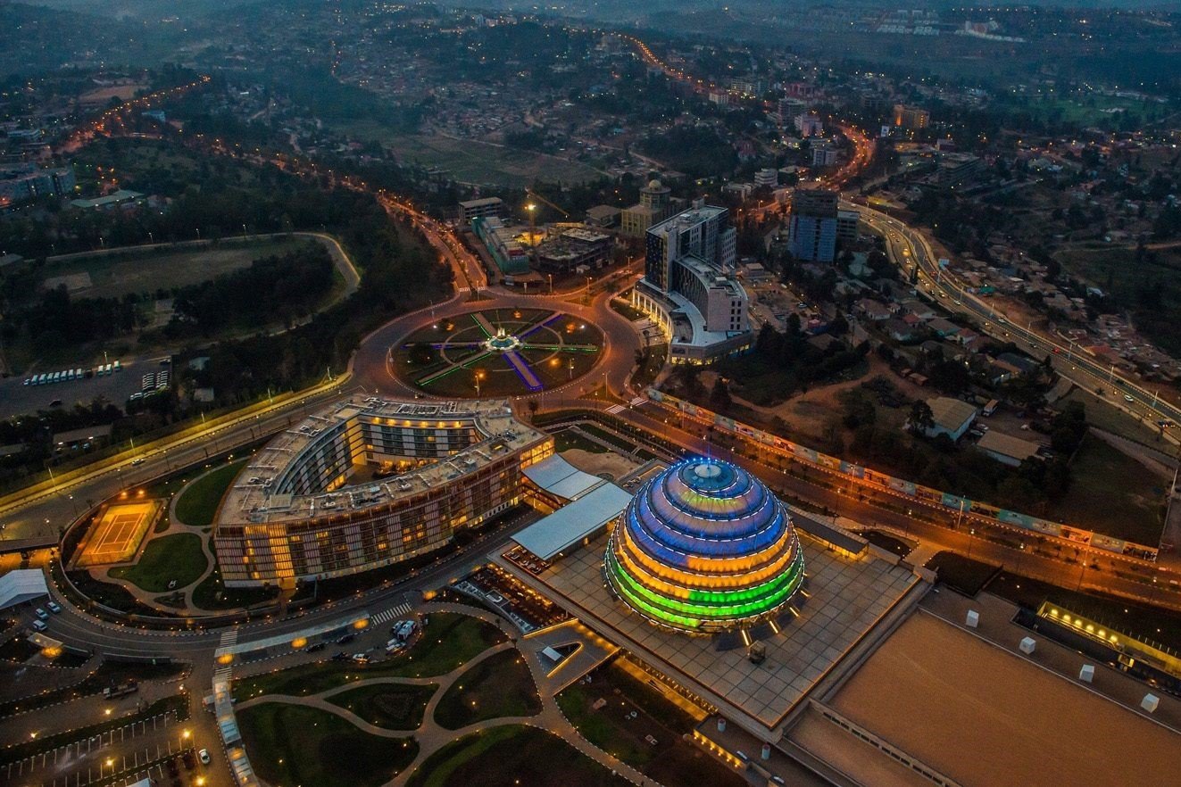 An aerial view of a cityscape at dusk featuring a roundabout with colorful lighting and a brightly illuminated, multicolored, conical building. Learning Expedition