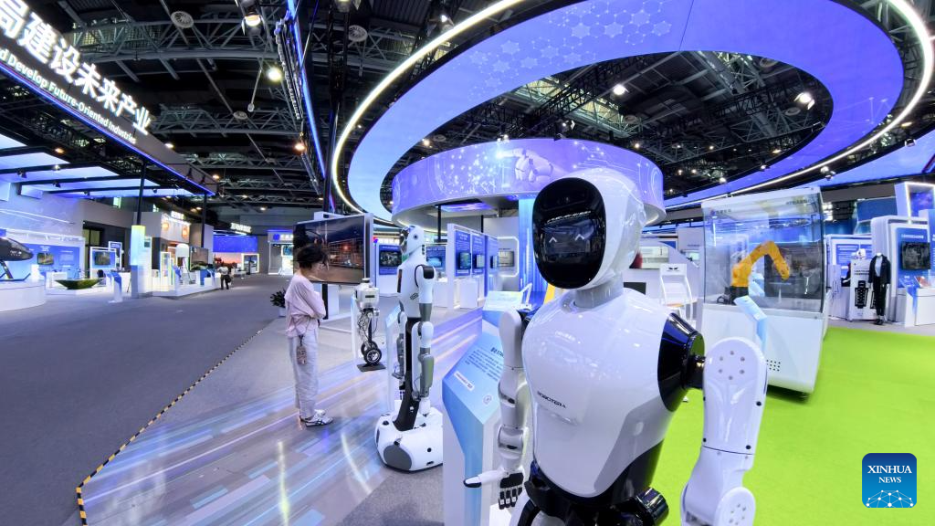 Robots displayed at a technology exhibition with a person observing them, futuristic design, bright blue lighting, and various technology exhibits in the background.