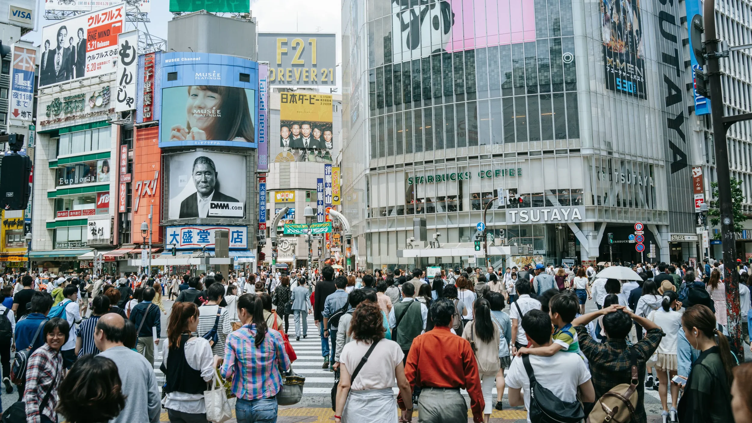 Crowds crossing Shibuya in Tokyo beneath advertising billboards, illustrating advertising-led consumer discovery