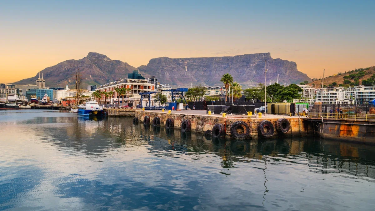 View of a harbor with boats, a promenade with palm trees, buildings, and the Flatiron Building in the background at sunset. Learning Expedition