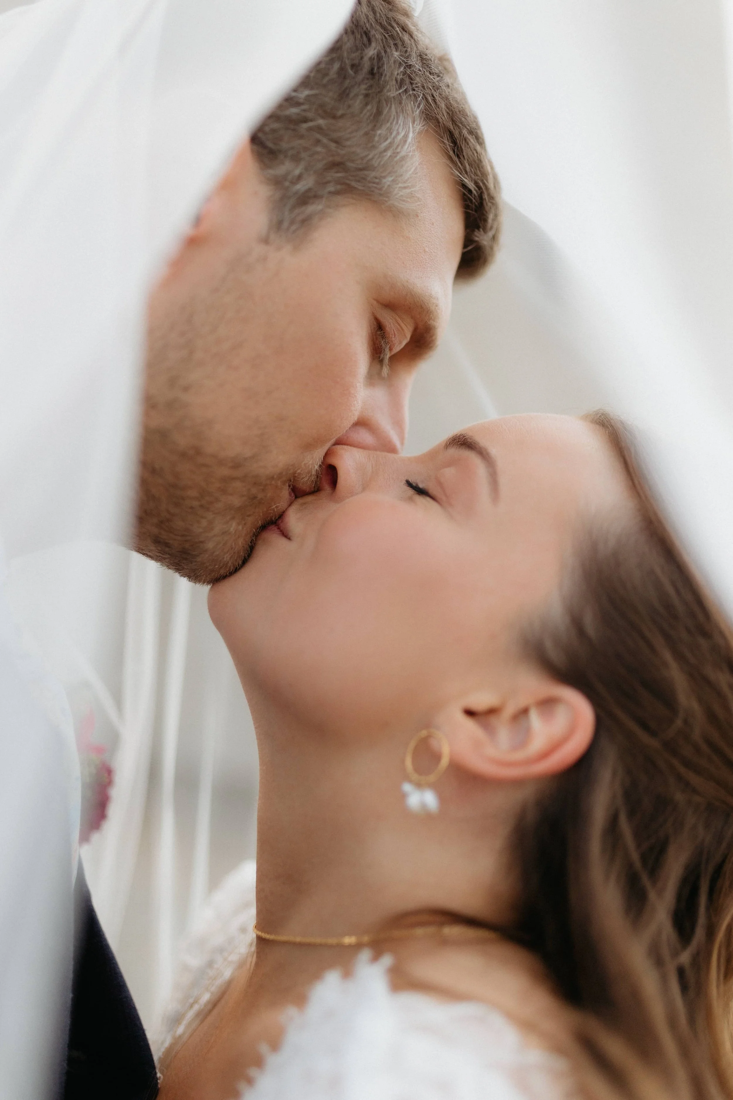 portrait serre sur maries pendant qu'ils s'embrassent sous voile mariee