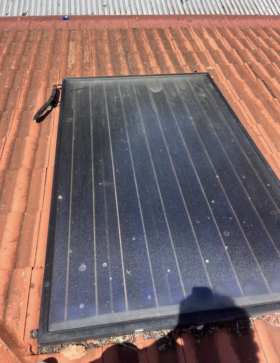 Solar hot water system which is covered in dust on a local Townsville roof