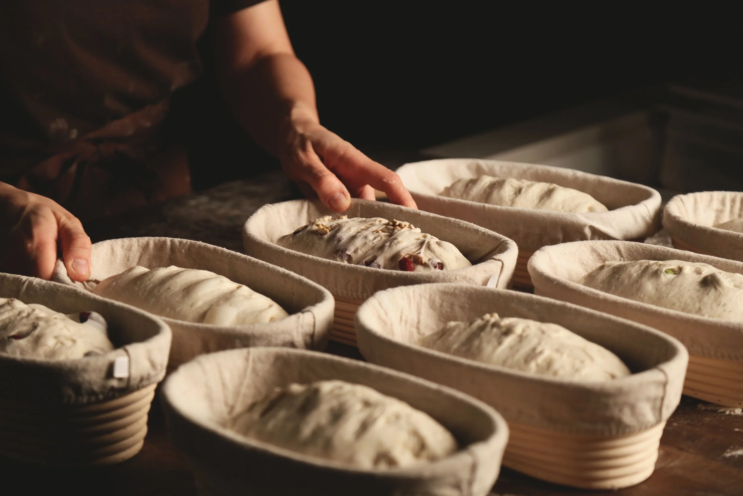 Person shaping dough in bannetons for bread baking.