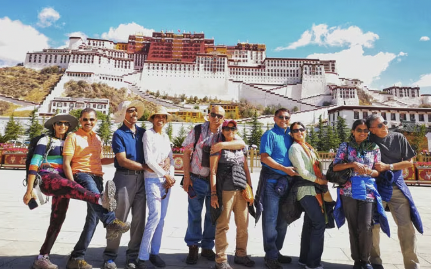 Group of tourists posing in front of Potala Palace in Lhasa, Tibet, on a sunny day.