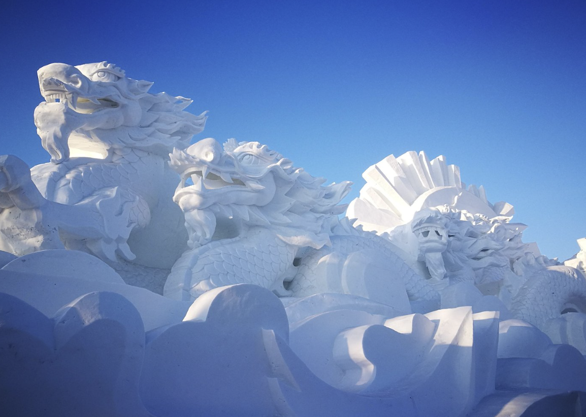 Snow sculpture of Chinese dragons and waves with a clear blue sky