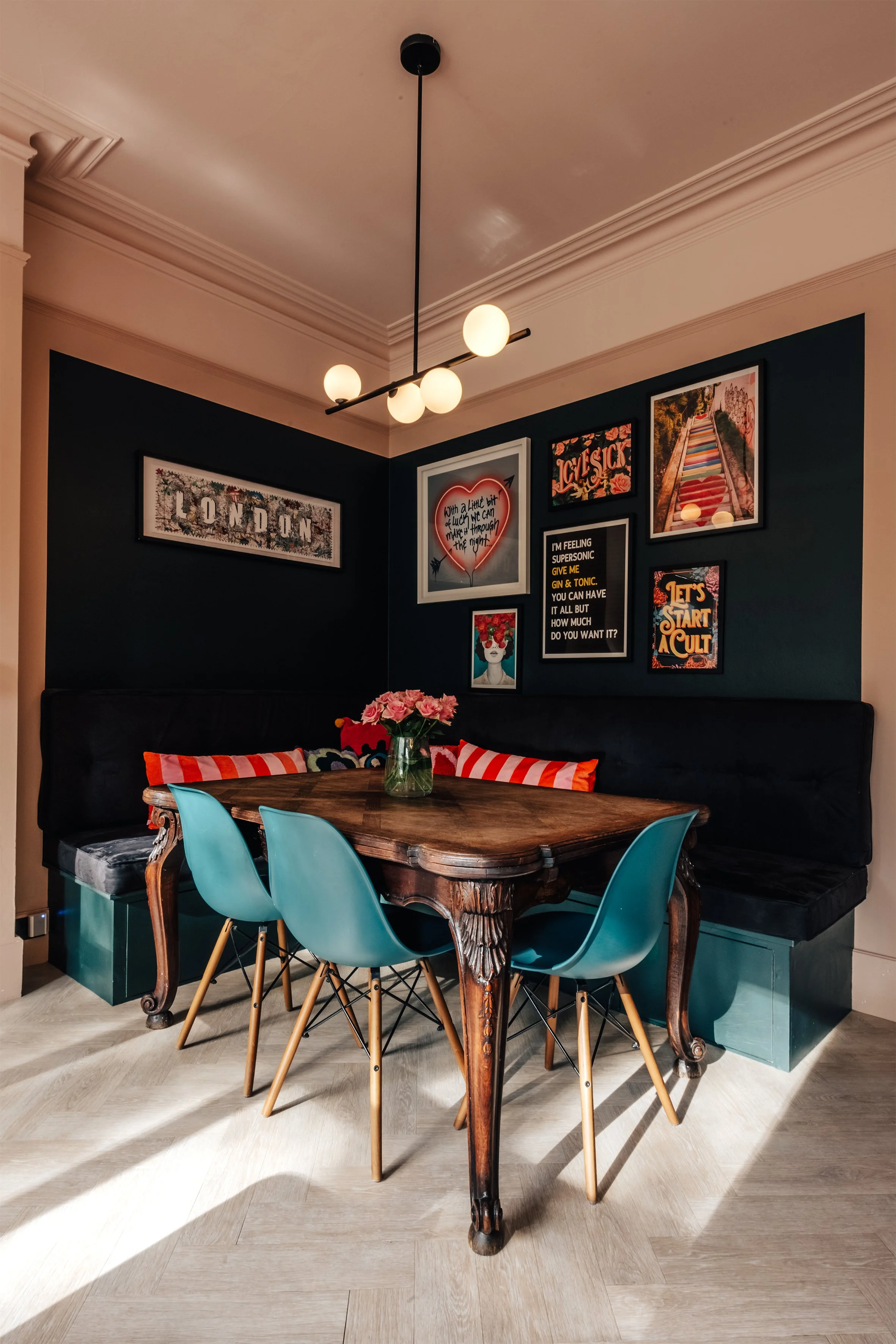 Cozy dining nook with a wooden table, blue chairs, and wall art.