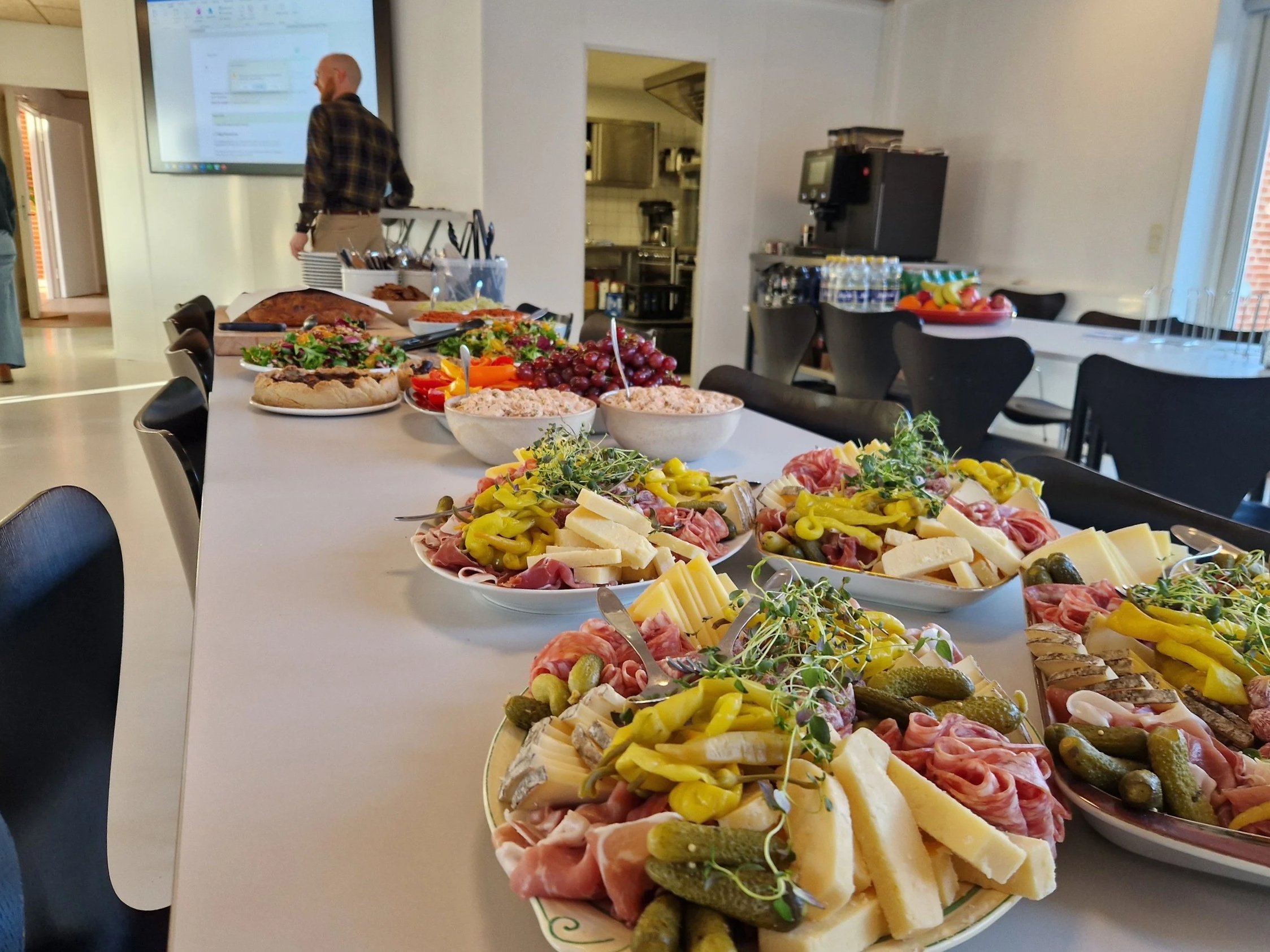 Et langt bord dækket med forskellig tapas-fade med forskellige oste, kød, tapenader, frugt og mikrogrønt.