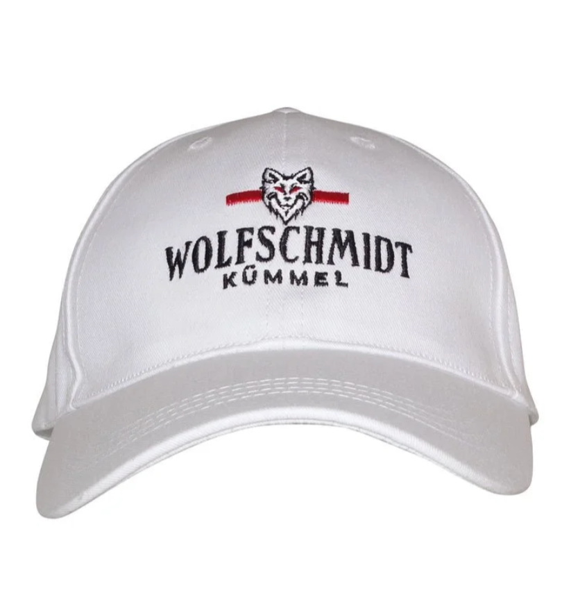 White baseball cap with embroidered wolf head and text 'WOLFSCHMIDT KÜMMEL' on front