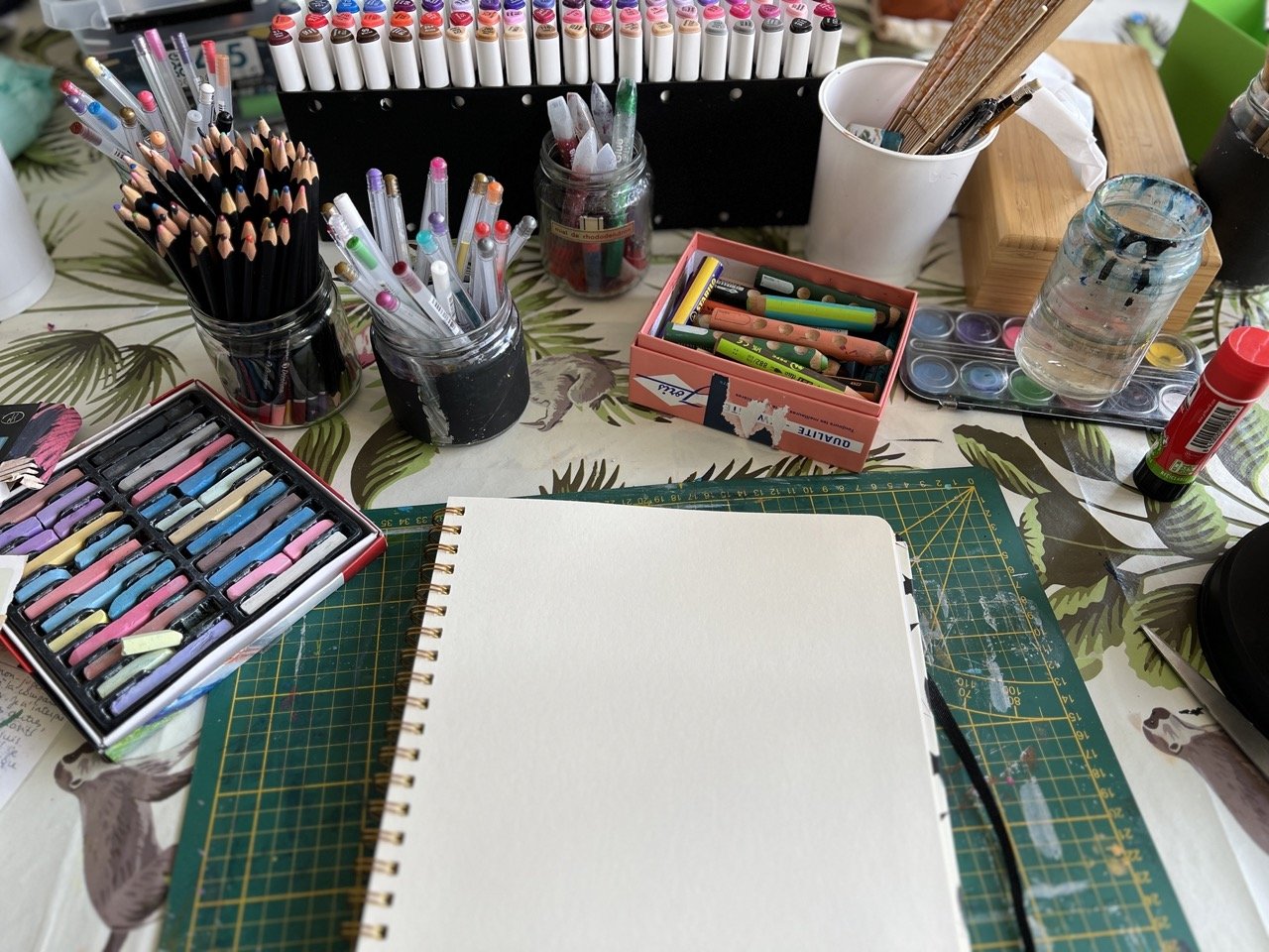 l'angoisse de la page blanche quand on veut créer dans son journal créatif - carnet ouvert sur une page blanche avec une multitude de matériel créatif coloré