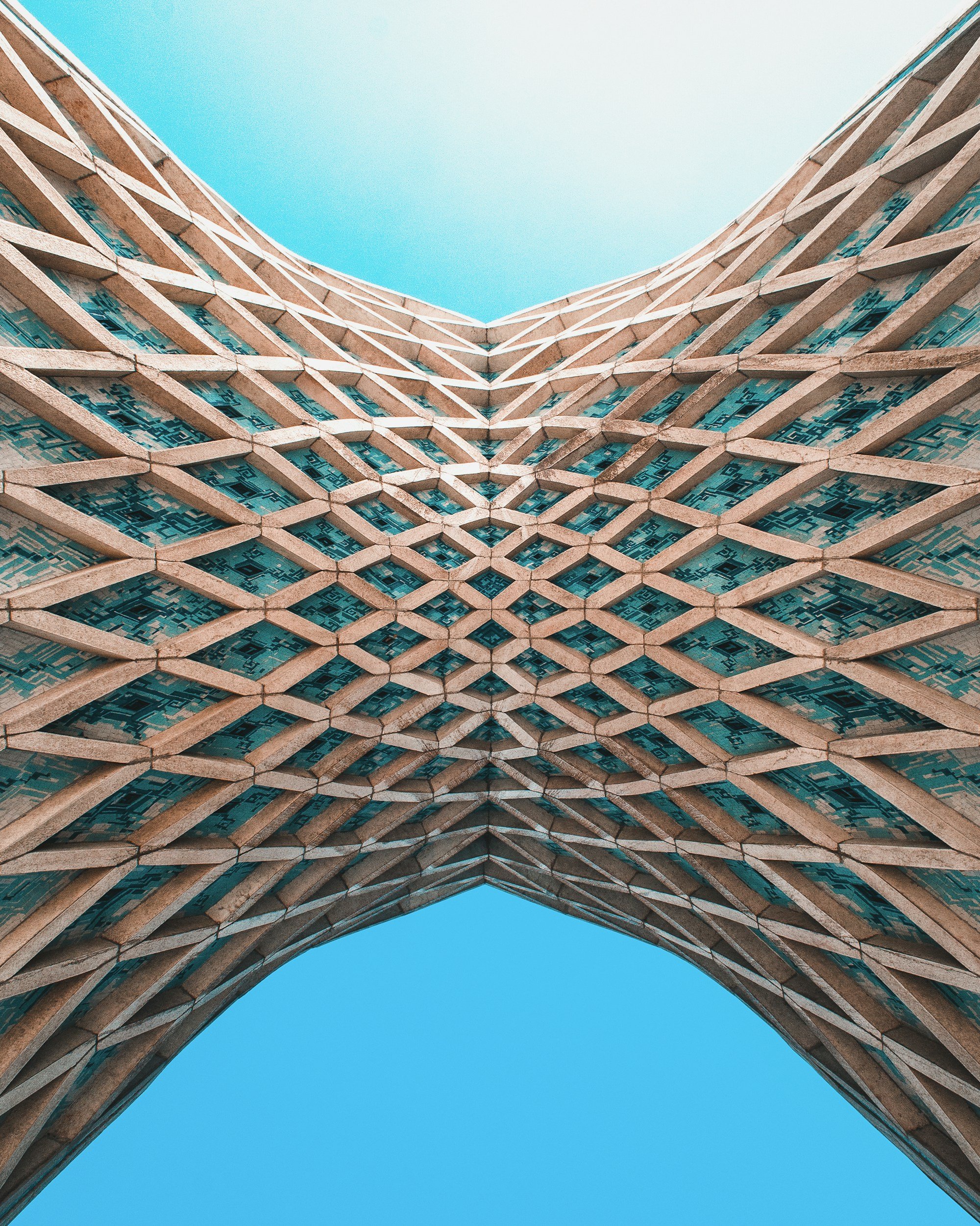 Looking up at a modern architectural building with a honeycomb-like facade and clear blue sky.