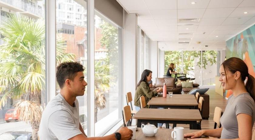 People talking and relaxing in a modern cafe with large windows and a bright interior.
