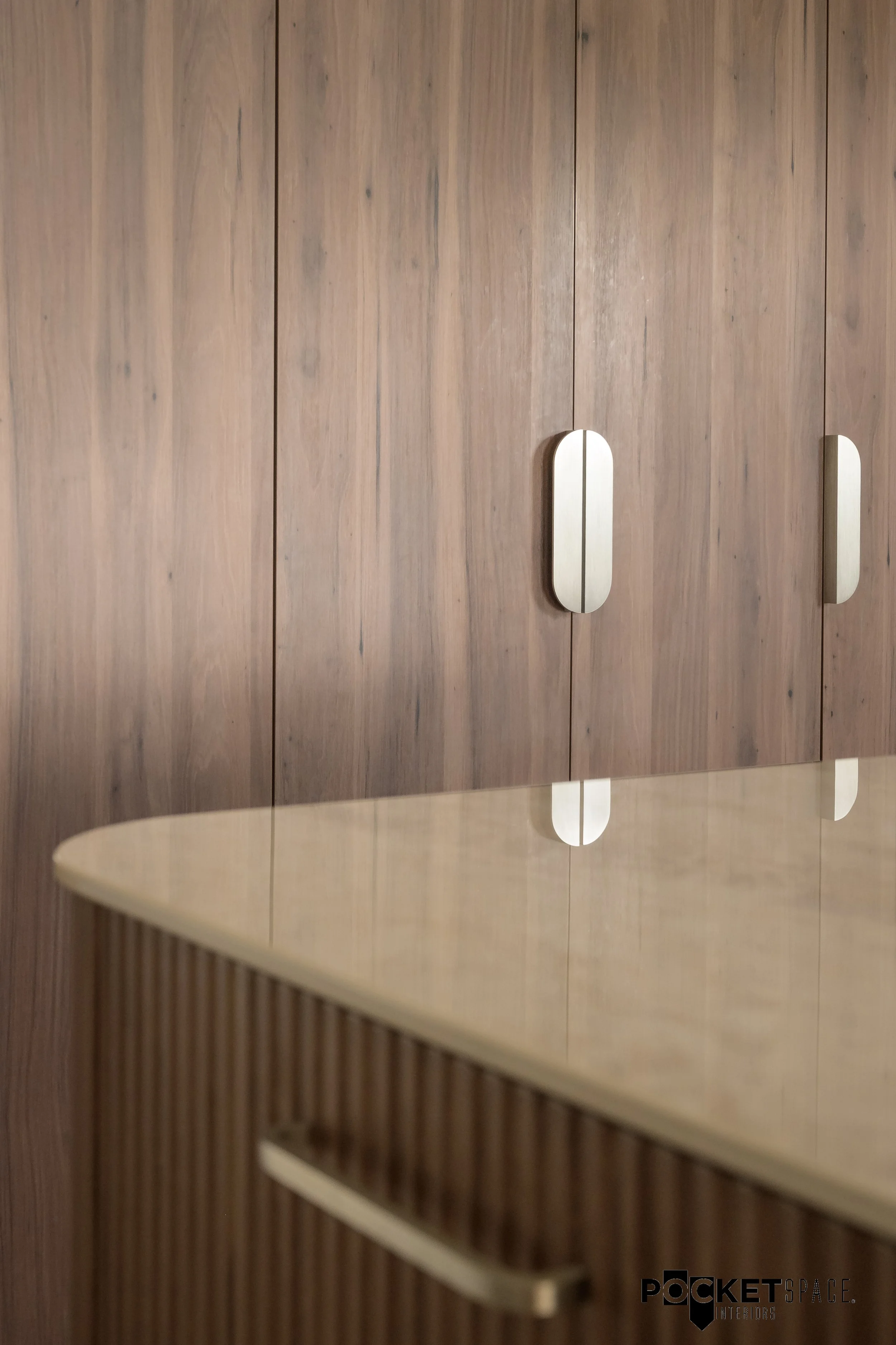 Wooden closet doors with modern metal handles and a polished countertop edge in a stylish interior design.