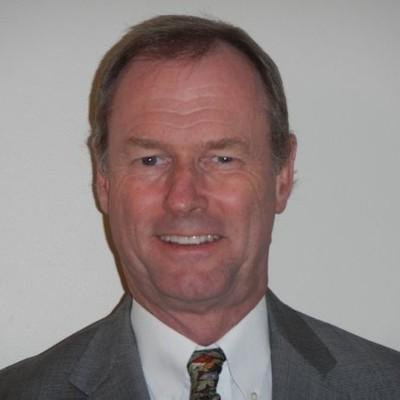 A middle-aged man in a suit smiling at the camera.