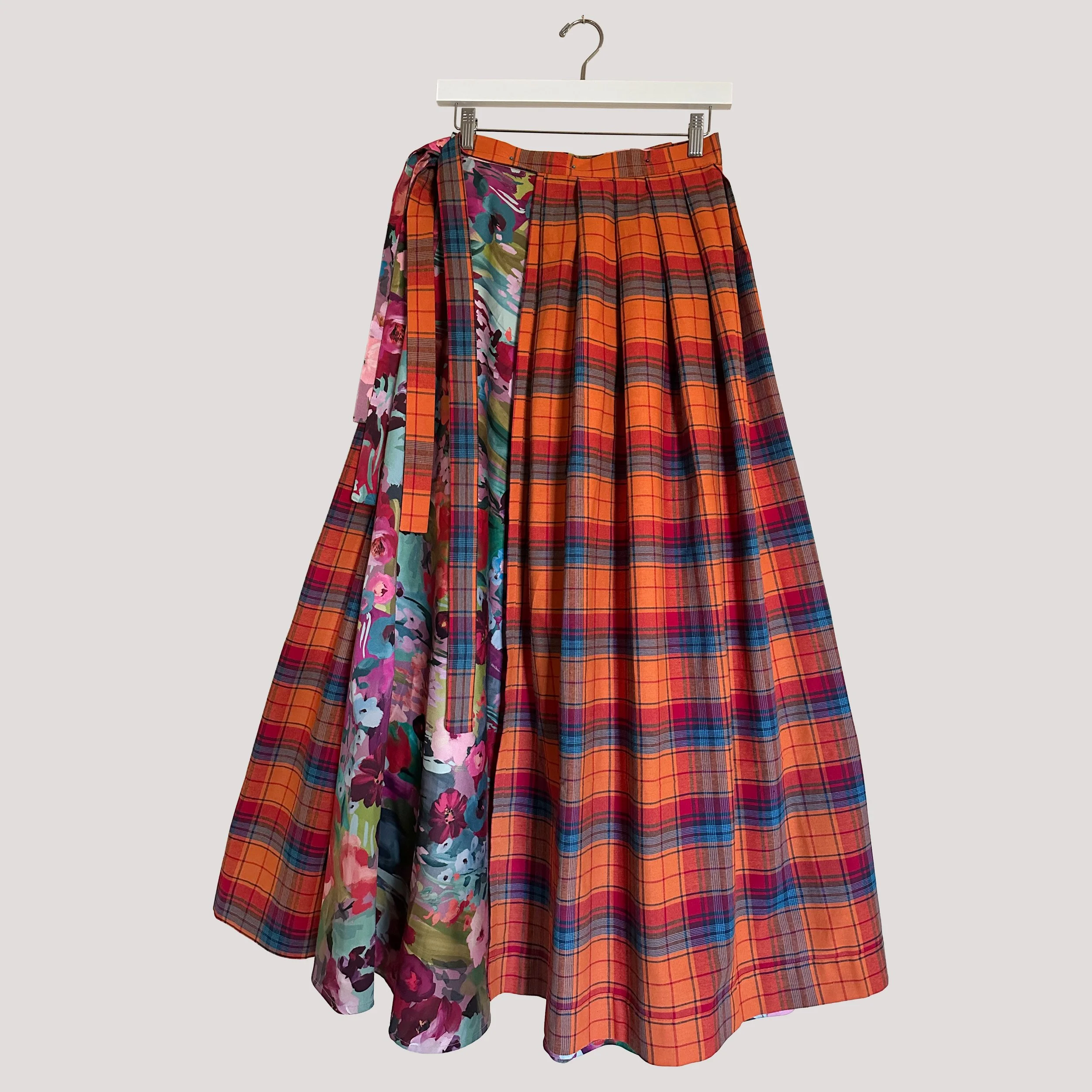 Reversible wrap midi skirt showing the tartan pleated side with structured silhouette.