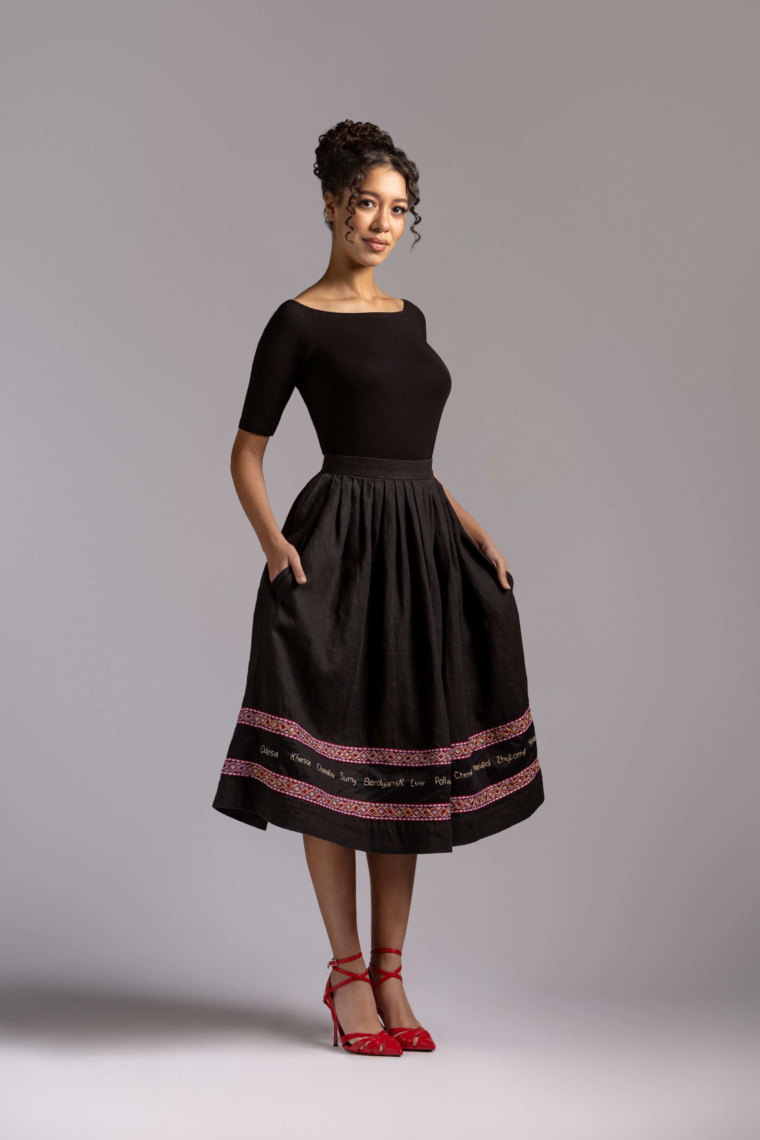 Model wearing a black linen midi skirt with traditional Ukrainian embroidery near the hem.