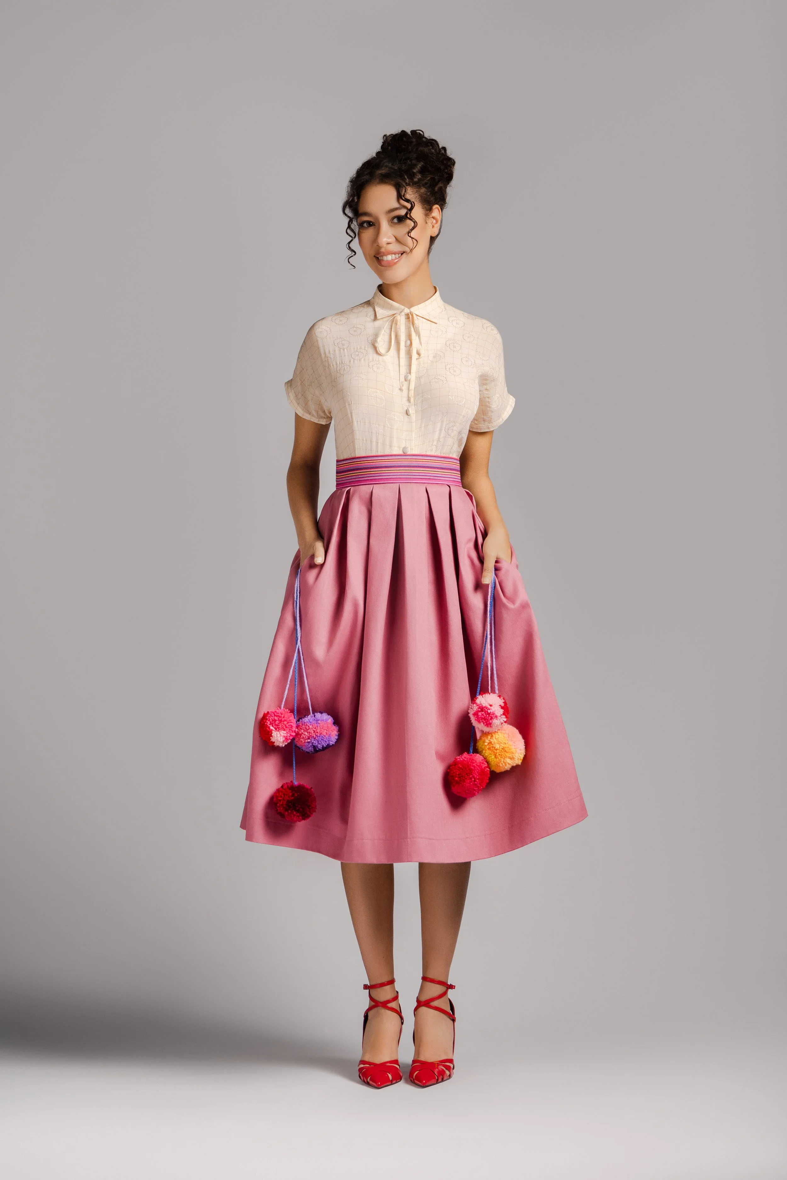 Pink midi skirt with hidden colorful pompom details inside pockets.